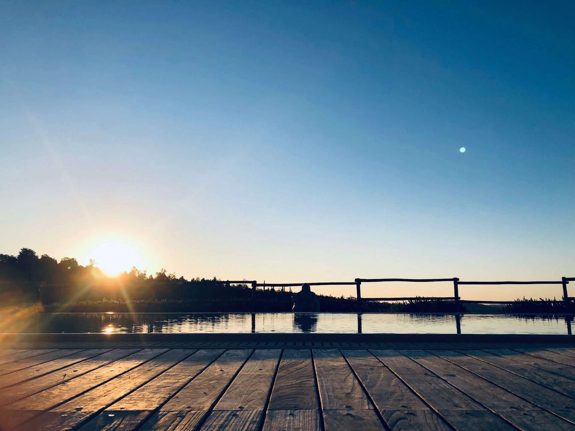 Sunrise reflecting on the infinity pool deck at Conti di San Bonifacio Wine Resort in Tuscany